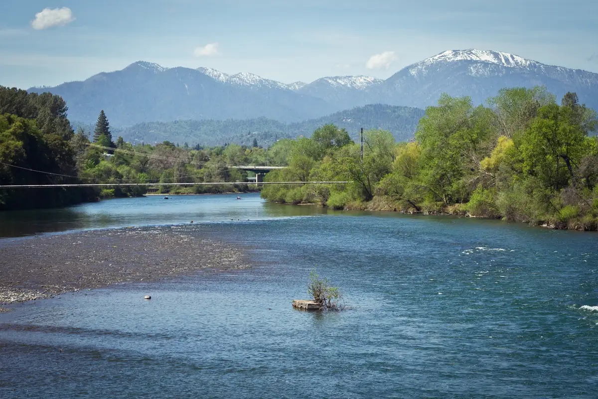The Sacramento River flowing through Shasta County with mountains behind